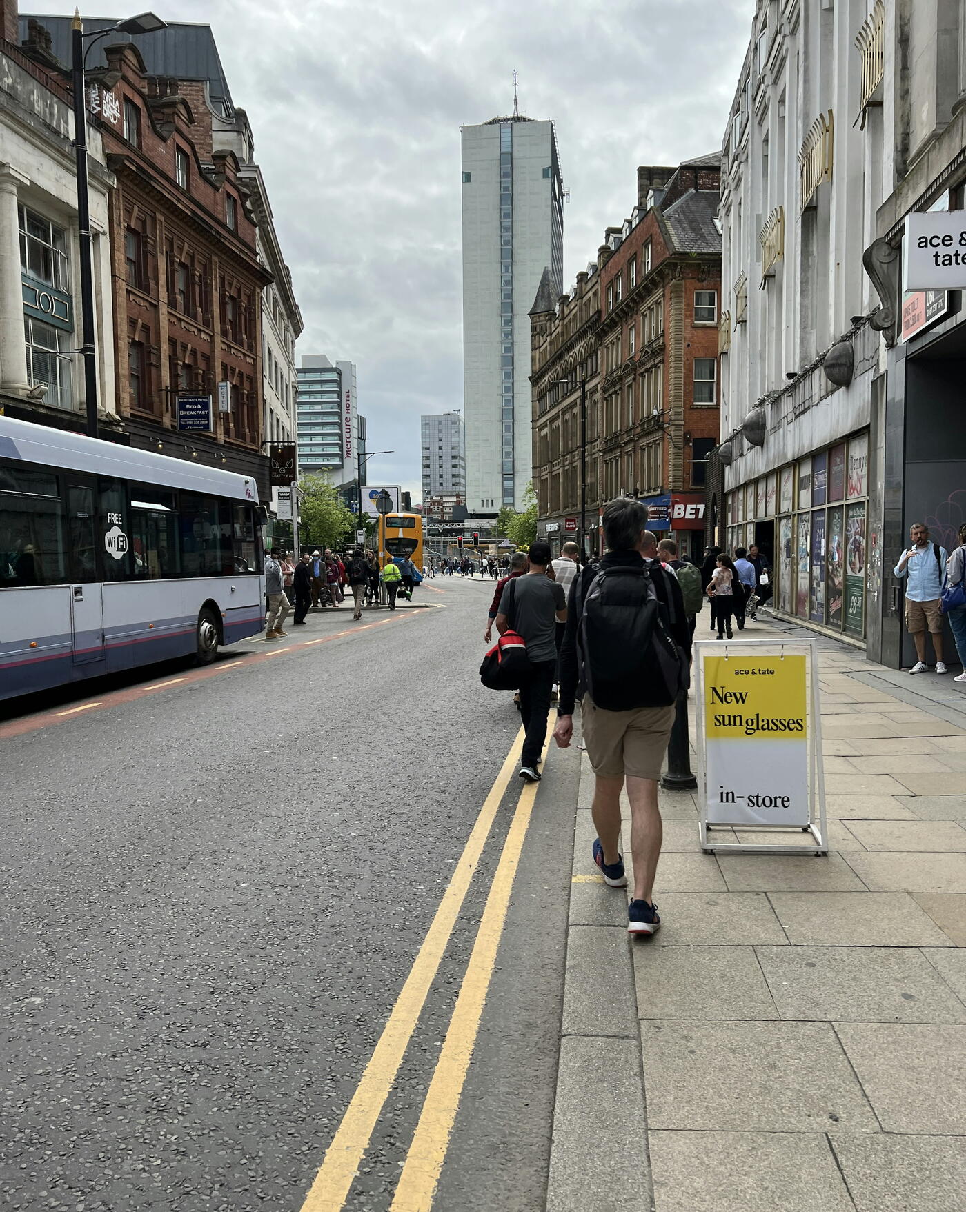 A busy Manchester street near Piccadilly, with a bus and red-brick buildings